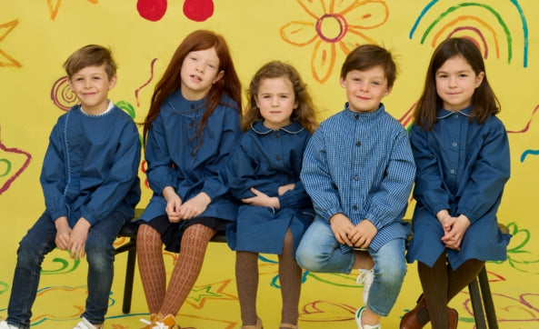 Cinq enfants assis en tabliers d'école bleus
