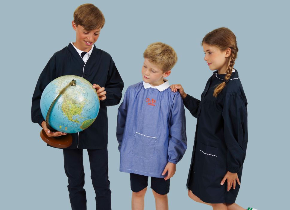 Trois enfants en tabliers marine et bleu jean brodés au logo de leur école